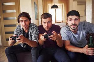 Group of friends have fun playing console game indoors at living room photo