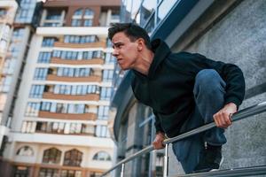 Young man doing parkour in the city at daytime. Conception of extreme sports photo