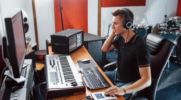 ingeniero de sonido en auriculares trabajando y mezclando música en interiores en el estudio foto