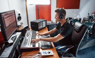 ingeniero de sonido en auriculares trabajando y mezclando música en interiores en el estudio foto