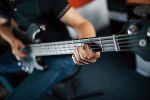 Close up view of musician plays bass guitar indoors photo