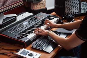 tocando el teclado midi. ingeniero de sonido trabajando y mezclando música en interiores en el estudio foto