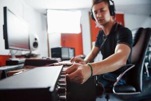 ingeniero de sonido en auriculares trabajando y mezclando música en interiores en el estudio foto