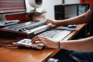 tocando el teclado midi. ingeniero de sonido trabajando y mezclando música en interiores en el estudio foto