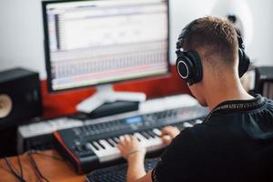 Sound engineer in headphones working and mixing music indoors in the studio photo