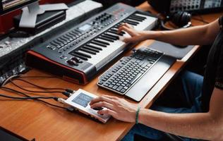 Playing midi keyboard. Sound engineer working and mixing music indoors in the studio photo