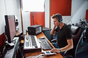 ingeniero de sonido en auriculares trabajando y mezclando música en interiores en el estudio foto