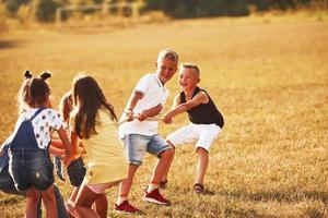 Kids playing tug of war game in the beautiful meadow at sunny day photo