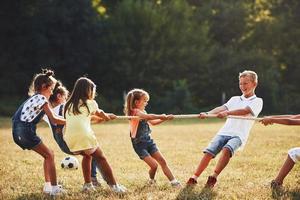 Kids playing tug of war game in the beautiful meadow at sunny day photo