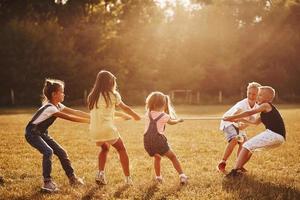 niños jugando tira y afloja en el hermoso prado en un día soleado foto