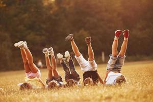 niños descansando juntos en el campo durante el día soleado. levantando las piernas foto