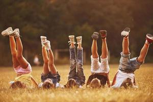 Kids resting in the field at sunny daytime together. Raising legs up photo