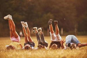 Kids resting in the field at sunny daytime together. Raising legs up photo