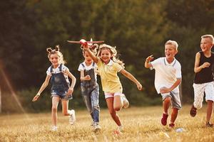 Group of kids having fun outdoors with red toy airplane in hands photo