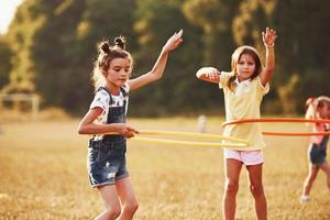 Girls with circle fitness tool. Group of kids have active weekend in the field photo