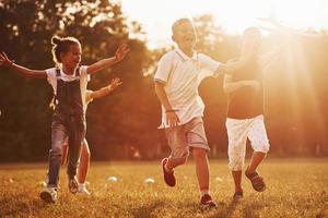 Group of kids have active weekend in the field. Illuminated by beautiful sunlight photo