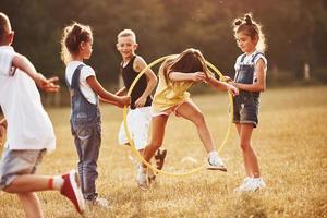 saltando a través de la herramienta de fitness circular. niños divirtiéndose en el campo foto