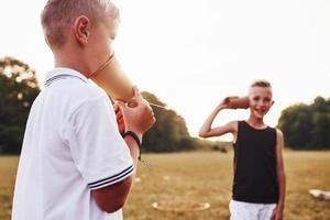 dos niños se paran en el campo y hablan usando una cuerda por teléfono foto