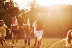 grupo de niños tiene un fin de semana activo en el campo. iluminado por la hermosa luz del sol foto