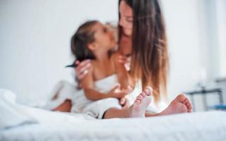 foto enfocada. la joven madre con su hija tiene un día de belleza en el interior de la habitación blanca