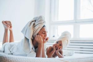 Having fun. Young mother with her daugher have beauty day indoors in white room photo