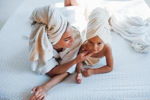 Having fun. Young mother with her daugher have beauty day indoors in white room photo