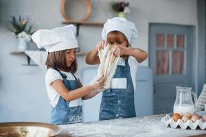 niños de familia con uniforme de chef blanco preparando comida en la cocina foto