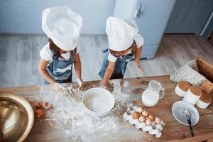 Top view. Family kids in white chef uniform preparing food on the kitchen photo