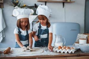 Family kids in white chef uniform preparing food on the kitchen photo