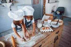 niños de familia con uniforme de chef blanco preparando comida en la cocina foto