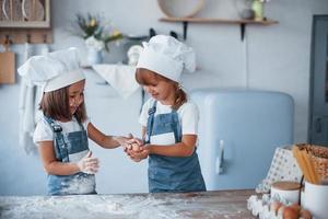 jugando con huevos. niños de familia con uniforme de chef blanco preparando comida en la cocina foto