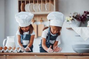 niños de familia con uniforme de chef blanco preparando comida en la cocina foto