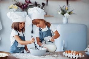 Family kids in white chef uniform preparing food on the kitchen photo