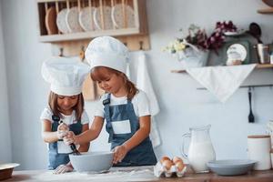 niños de familia con uniforme de chef blanco preparando comida en la cocina foto