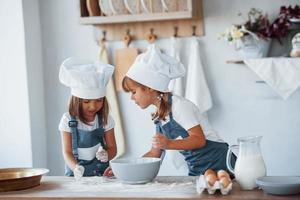 Family kids in white chef uniform preparing food on the kitchen photo