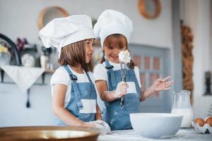 Family kids in white chef uniform preparing food on the kitchen photo