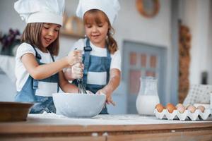 niños de familia con uniforme de chef blanco preparando comida en la cocina foto