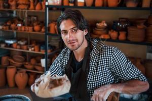 Handsome ceramist packages his fresh product in the paper photo