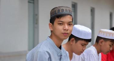 Asian muslim or islamic boys sitting with muslim boys in a row to pray or to do the religious activity, soft and selective focus. photo