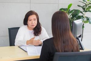 una mujer asiática se sienta en una silla mientras se entrevista de trabajo con el gerente de negocios en la oficina. foto