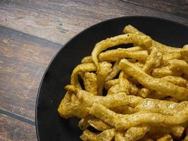 pork rind in black plate on wood table for food concept photo