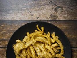 pork rind in black plate on wood table for food concept photo