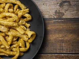 pork rind in black plate on wood table for food concept photo