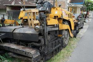 acabadora de asfalto, detalle frontal de una máquina de construcción de carreteras estacionada al costado de la carretera foto