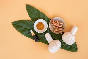 Top view of herbal compress ball with Thai herbal, turmeric, essential oil and bar soap on orange pastel background. Spa background concept. photo