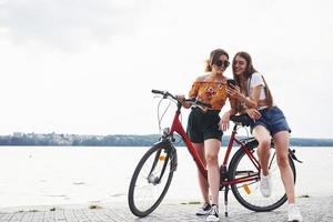 dos amigas en bicicleta se divierten en la playa cerca del lago foto