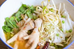 Rice noodles with chicken feet on soup bowl on wooden table food background - Thai food thai rice noodles spicy soup curry with fresh vegetable photo