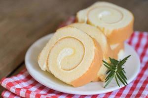 sponge cake roll slices sweets dessert cream roll vanilla snacks and food concept - Swiss Roll Cake, Cake roll on plate cake with rosemary on table photo