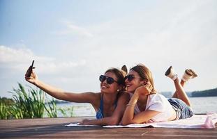 dos chicas en la playa tumbadas en el suelo y disfrutando de la cálida luz del sol foto