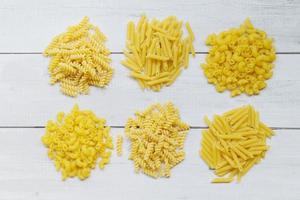 Raw pasta various kinds of uncooked pasta macaroni spaghetti and noodles - top view, Italian food culinary concept, Collection of different raw pasta on cooking table for cooking food photo